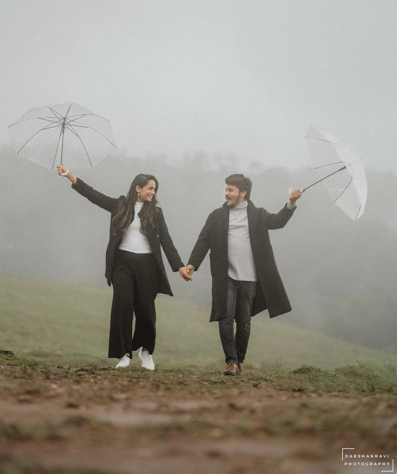 A couple walking with umbrellas through the mist — Darshan Ravi Photography