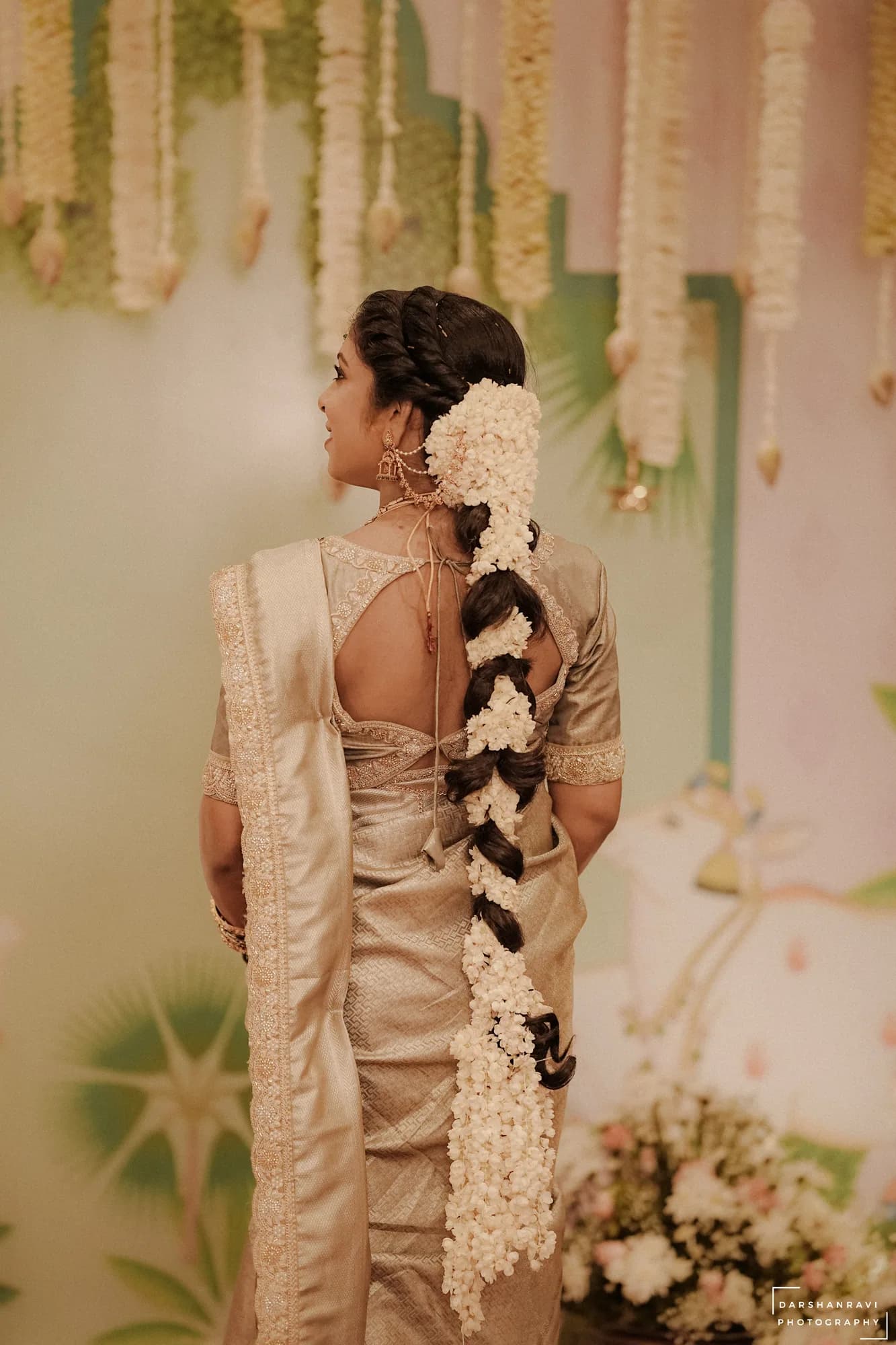 A bride photographed from behind, jasmine in her braid — Darshan Ravi Photography